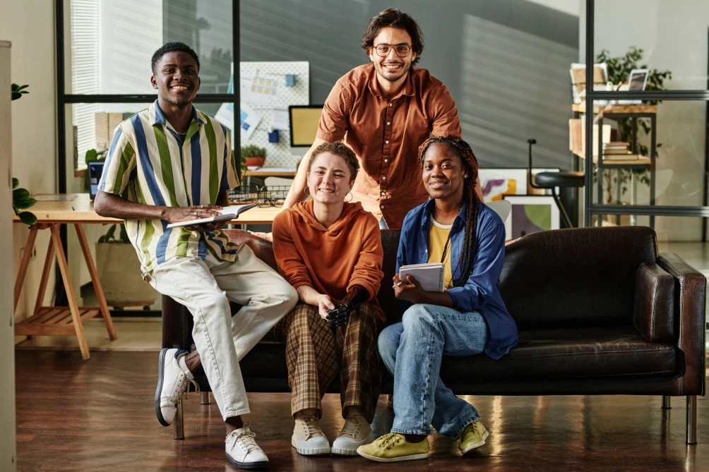 Group of diverse friends sitting on couch and smiling at camera