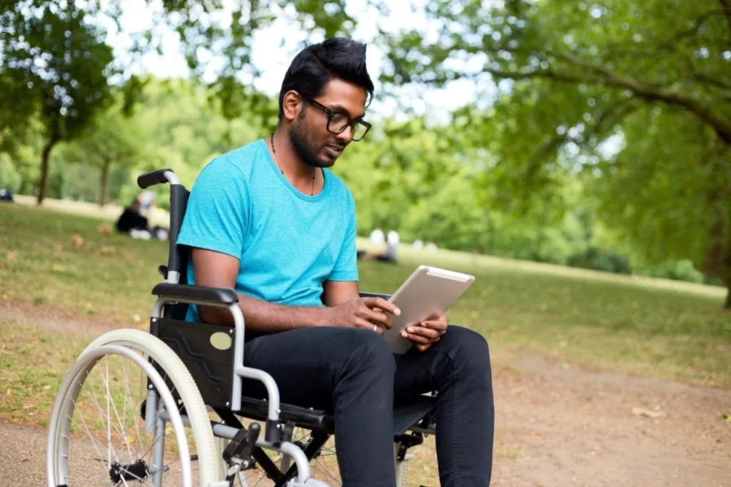 Indian man in wheelchair looking at tablet