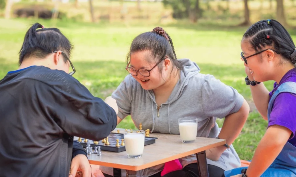 Three friends with down syndrome playing chess in the park