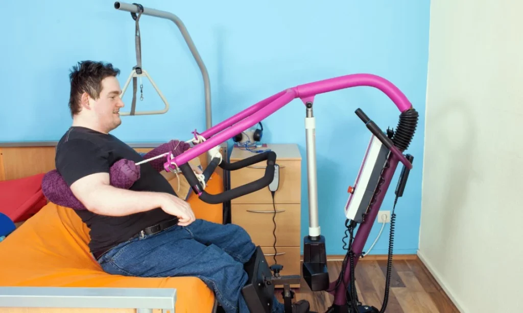 Disabled man in hoist in bedroom smiling