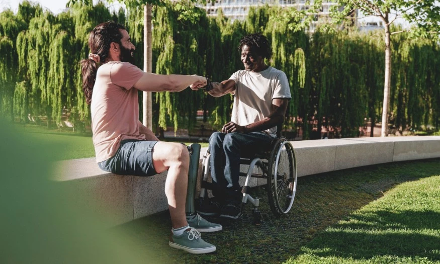 Two disabled friends in the park fist pumping
